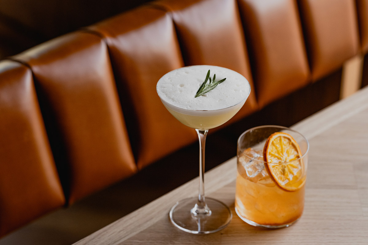 Leather booth and wooden table with fancy cocktails.